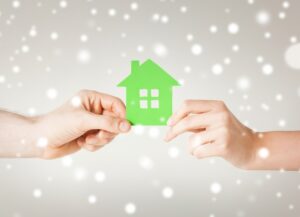 hands-holding-green-cutout-of-house-with-snow