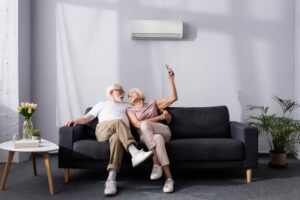 senior-couple-sit-on-sofa-change-temp-of-mini-split-with-remote