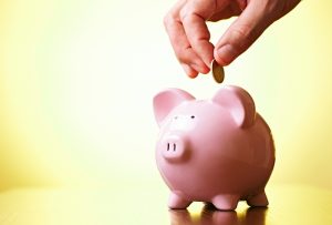 hand-putting-coin-into-piggy-bank