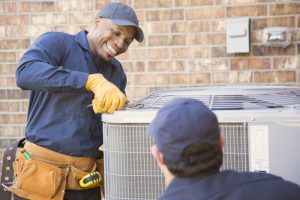smiling-HVAC-technician-performing-AC-maintenance